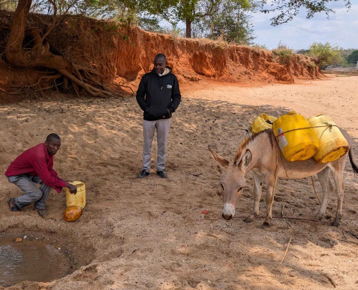 A dry riverbed in the project region — water carried home in jerry cans.